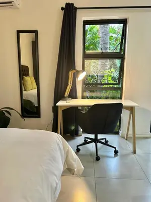 a bedroom with a desk and a bed and a window at Apartment close to Menlyn Maine in Pretoria