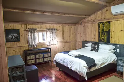 a bedroom with a bed in a room with wooden walls at Letlotse Lodge in Hammanskraal