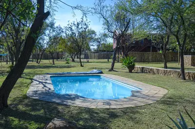 a swimming pool in a yard with a tree at Letlotse Lodge in Hammanskraal