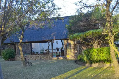 a stone house with a porch with a bike in front of it at Letlotse Lodge in Hammanskraal