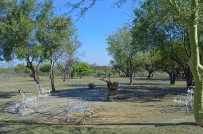 a group of white chairs sitting in a park at Letlotse Lodge in Hammanskraal