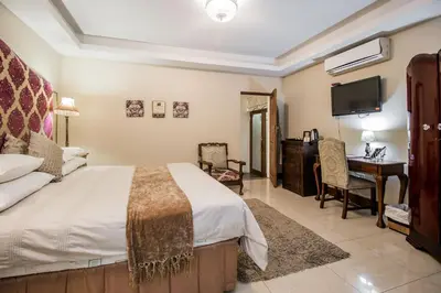 a bedroom with a bed and a desk and a television at Villa Amor in Pretoria