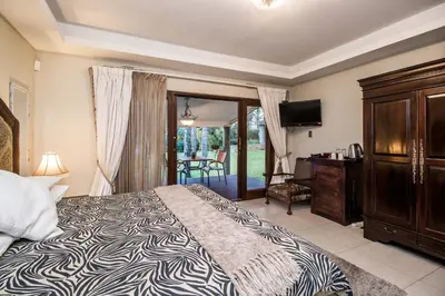 a bedroom with a bed and a dresser and a television at Villa Amor in Pretoria
