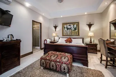 a bedroom with a bed and a desk and a table at Villa Amor in Pretoria