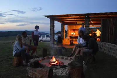 a group of people sitting around a fire at Woolly Bugger Farm in Tonteldoos