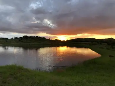 a sunset over a body of water with the sun setting at Woolly Bugger Farm in Tonteldoos