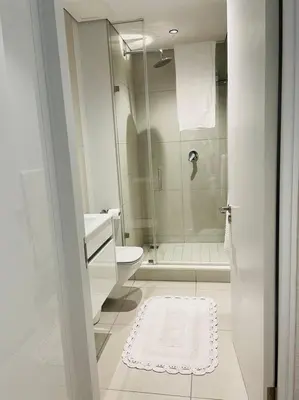 a white bathroom with a shower and a toilet at Ellipse Waterfall Luxury Apartment in Midrand