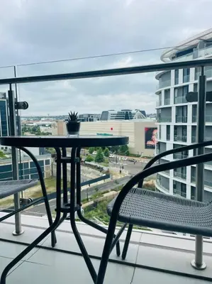 a table and chairs on a balcony with a view of a city at Ellipse Waterfall Luxury Apartment in Midrand