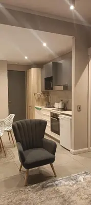 a living room with a chair and a kitchen at Menlyn Maine Trilogy Penthouse 42 in Pretoria