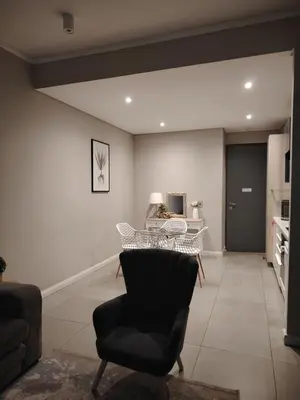 a living room with a table and a chair at Menlyn Maine Trilogy Penthouse 42 in Pretoria