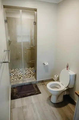 a bathroom with a shower with a toilet and a glass shower stall at Ruzelle Family House in Hazyview