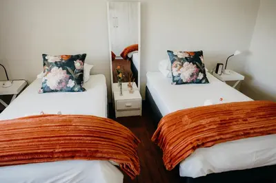 two beds in a small room with orange blankets at Ruzelle Family House in Hazyview