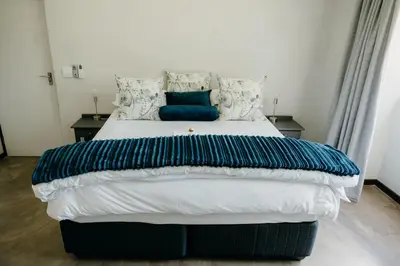 a large bed with blue and white sheets and pillows at Ruzelle Family House in Hazyview