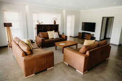 a living room with two couches and a tv at Ruzelle Family House in Hazyview