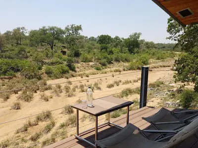a table with a bottle of water sitting on a deck at Greenfire Game Lodge in Balule Game Reserve