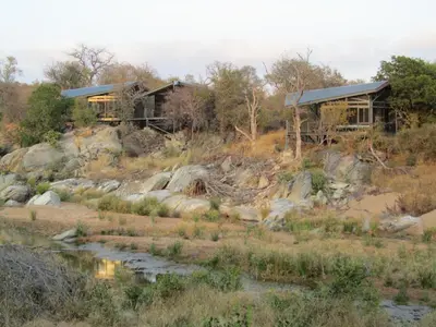 a house on a hill next to a river at Greenfire Game Lodge in Balule Game Reserve