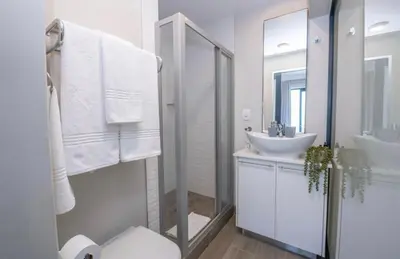 a white bathroom with a sink and a mirror at The Regency Cosy Apartment- 419 in Pretoria