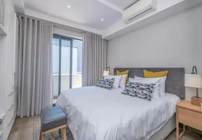a white bedroom with a large bed and a window at The Regency Cosy Apartment- 419 in Pretoria