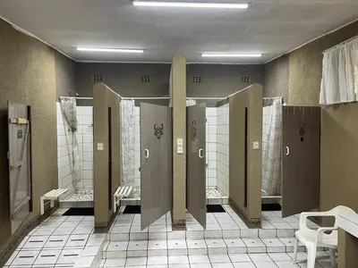 a public restroom with stalls and toilets in a room at De Rust Campsite in Hammanskraal