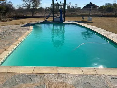 a large blue pool with a playground in a yard at De Rust Campsite in Hammanskraal