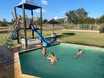 a group of kids playing in a swimming pool at De Rust Campsite in Hammanskraal