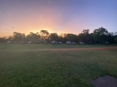 a field with cars parked in a park at sunset at De Rust Campsite in Hammanskraal