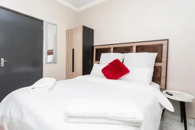 a bedroom with a large white bed with a red pillow at Botanik in Pretoria