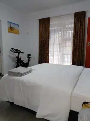 a bedroom with a white bed with a window at The Plum in Louis Trichardt