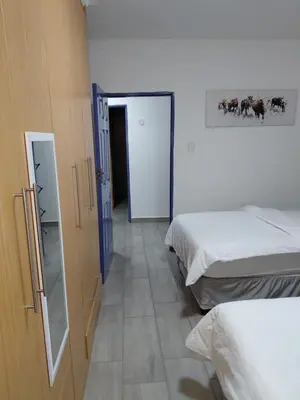 a room with two beds and a door to a hallway at The Plum in Louis Trichardt