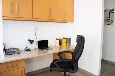 a desk with a laptop and a black chair at The Plum in Louis Trichardt