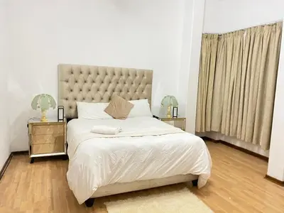 a bedroom with a large bed and two night stands at Tuscany Guesthouse in Midrand