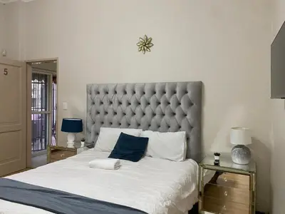 a bedroom with a large bed with a blue pillow at Tuscany Guesthouse in Midrand