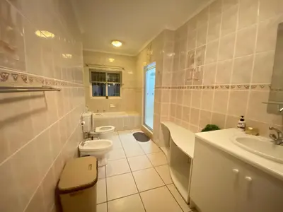 a white bathroom with a toilet and a sink at Tuscany Guesthouse in Midrand