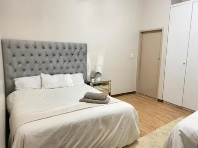 a bedroom with a large bed with a gray headboard at Tuscany Guesthouse in Midrand