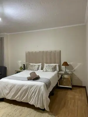 a bedroom with a large white bed and a lamp at Tuscany Guesthouse in Midrand
