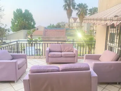 a patio with purple chairs and couches on a balcony at Tuscany Guesthouse in Midrand