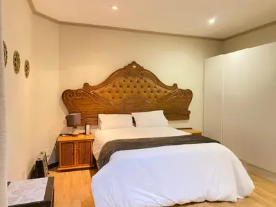 a bedroom with a large bed with a wooden headboard at Tuscany Guesthouse in Midrand