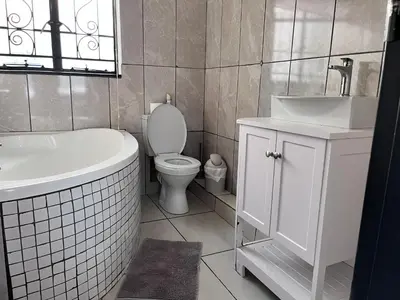 a bathroom with a tub and a toilet and a sink at Genesis Guesthouze in Bela-Bela