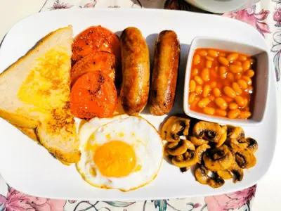 a plate of breakfast food with eggs sausage beans and mushrooms at Genesis Guesthouze in Bela-Bela
