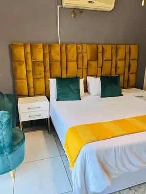 a bedroom with two beds and a large headboard at Genesis Guesthouze in Bela-Bela