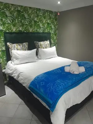 a large bed with blue and white sheets and pillows at Bokmakierie in Centurion