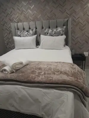 a bedroom with a large bed with white sheets and pillows at Bokmakierie in Centurion