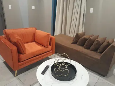 a living room with a couch and a chair and a table at Bokmakierie in Centurion