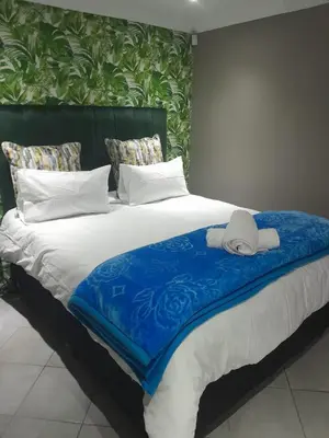 a large bed with a blue blanket on it at Bokmakierie in Centurion