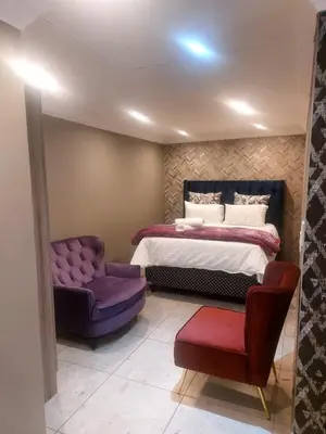 a bedroom with a bed and a purple chair at Bokmakierie in Centurion