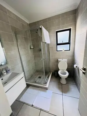 a bathroom with a shower and a toilet and a sink at The Blyde in Pretoria