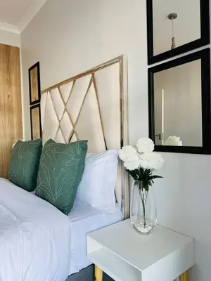 a vase of flowers on a table next to a bed at The Blyde in Pretoria