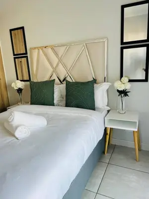 a bedroom with a large white bed with green pillows at The Blyde in Pretoria