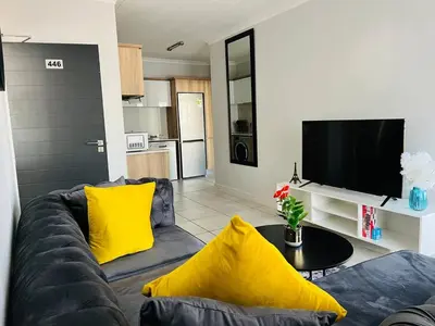 a living room with a couch and yellow pillows at The Blyde in Pretoria