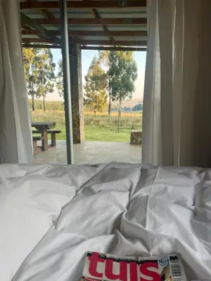 a book laying on a bed in front of a window at Kwaggaskop Farm Stoephuis in Dullstroom